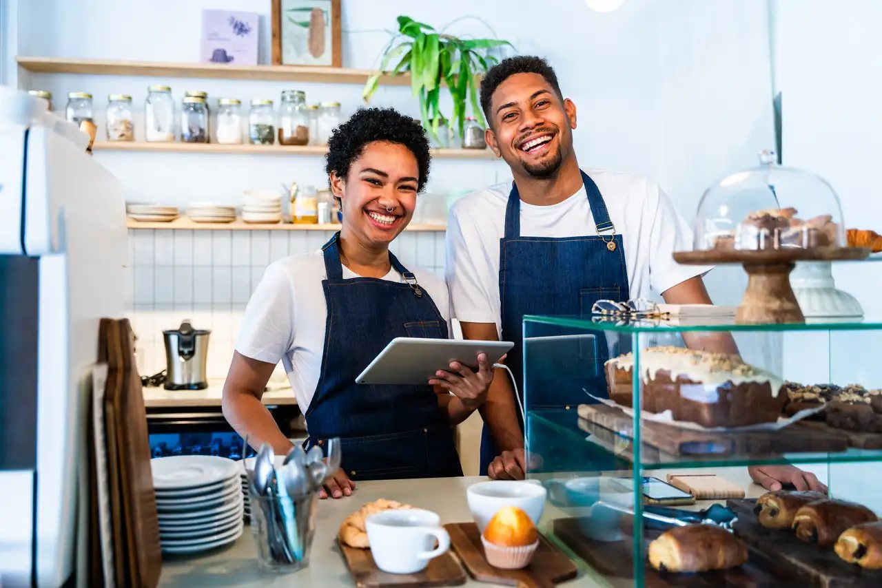 Two smiling owners behind the counter of a local bakery